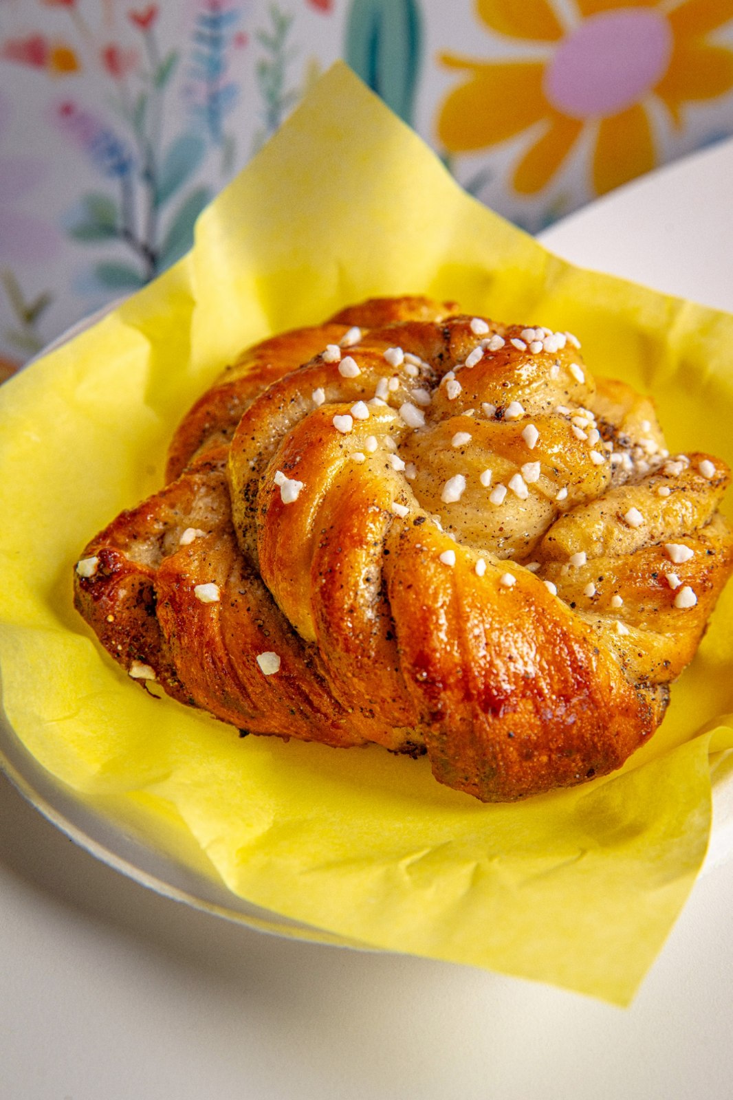 A golden Swedish cardamom bun topped with pearl sugar